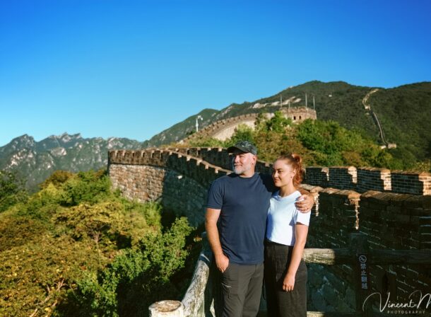An American couple posing for romantic pictures against the backdrop of Mutianyu Great Wall in Beijing, China. The Great Wall winds through the mountains, and the couple shows their love in the photos