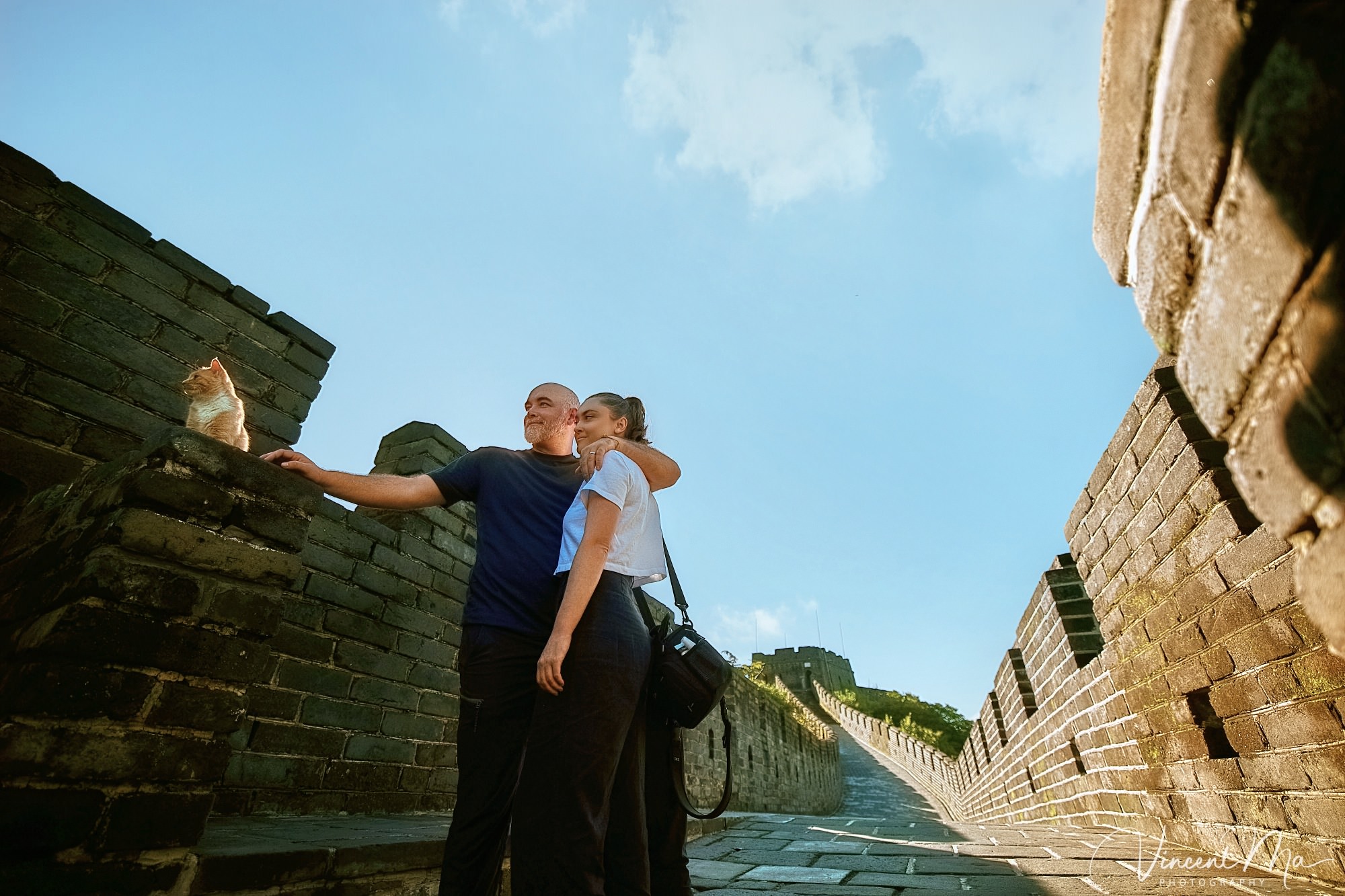 An American couple posing for romantic pictures against the backdrop of Mutianyu Great Wall in Beijing, China. The Great Wall winds through the mountains, and the couple shows their love in the photos