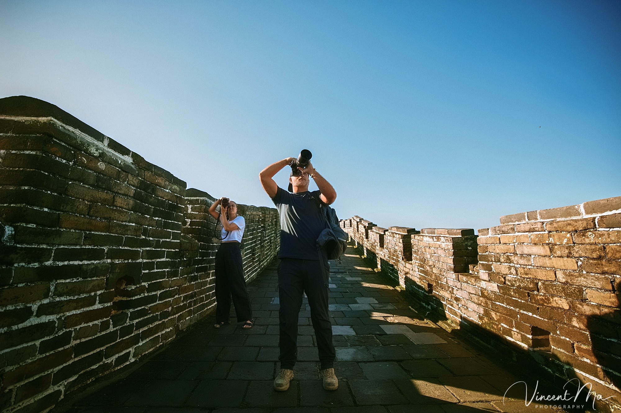 An American couple posing for romantic pictures against the backdrop of Mutianyu Great Wall in Beijing, China. The Great Wall winds through the mountains, and the couple shows their love in the photos
