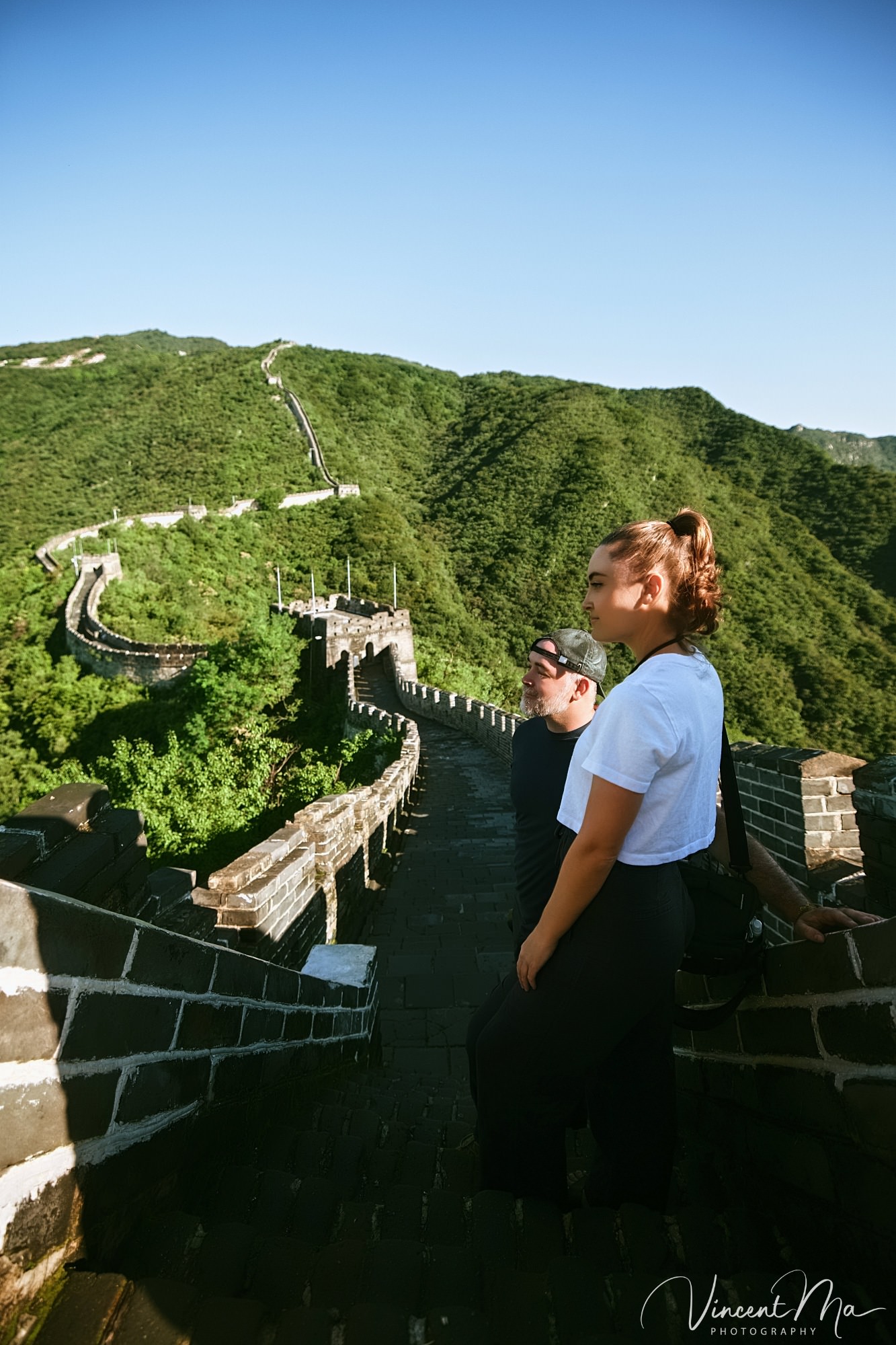 An American couple posing for romantic pictures against the backdrop of Mutianyu Great Wall in Beijing, China. The Great Wall winds through the mountains, and the couple shows their love in the photos