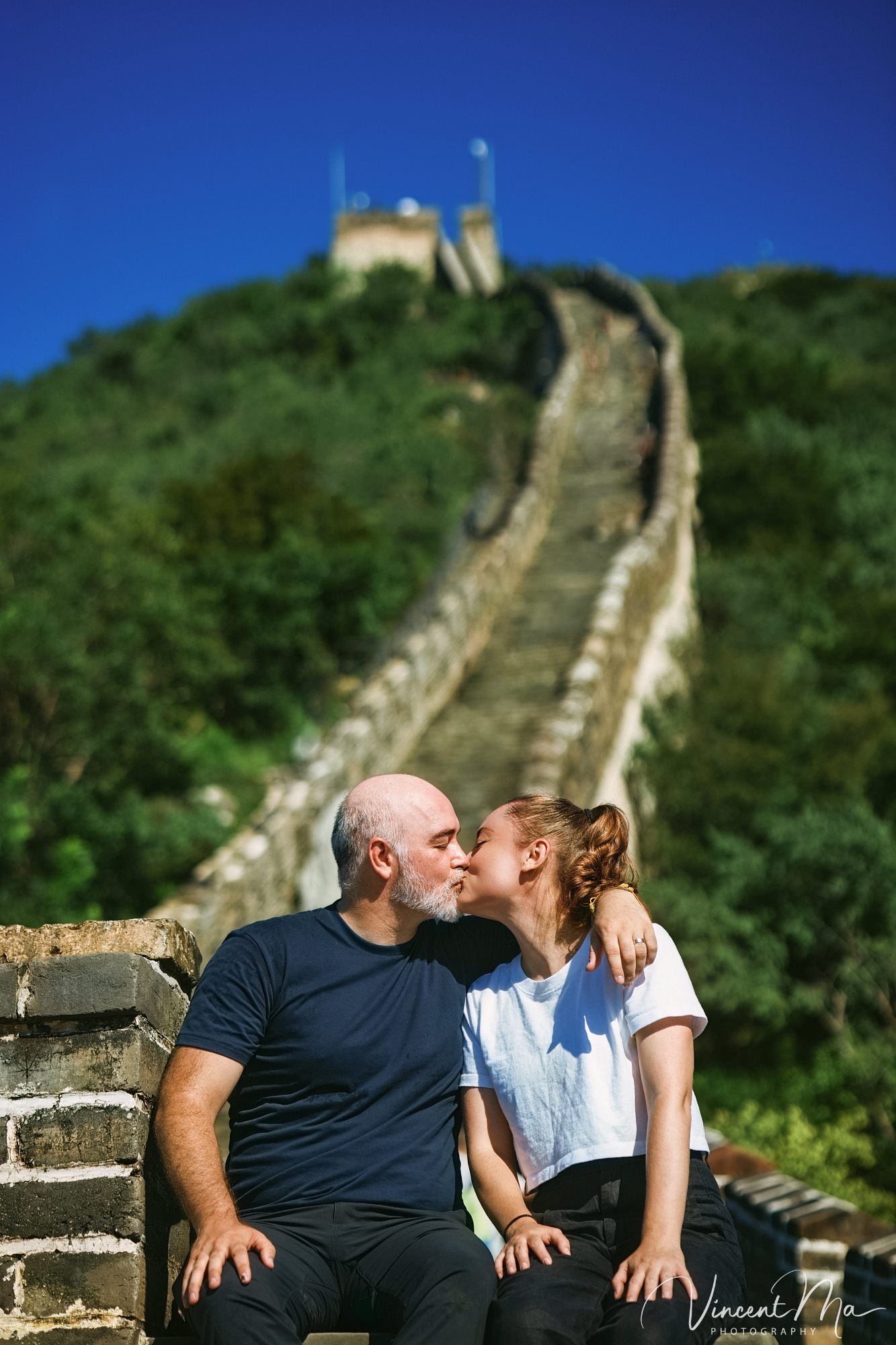 An American couple posing for romantic pictures against the backdrop of Mutianyu Great Wall in Beijing, China. The Great Wall winds through the mountains, and the couple shows their love in the photos