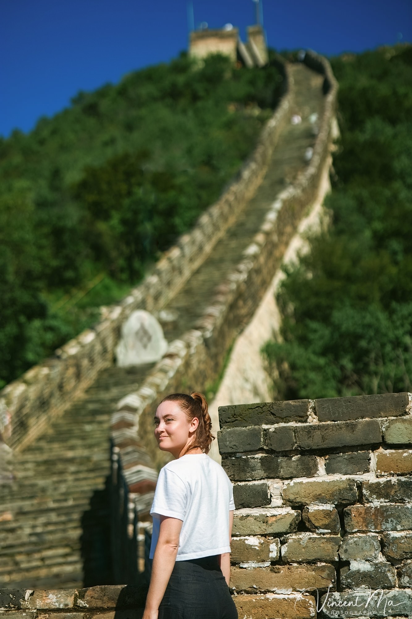 An American couple posing for romantic pictures against the backdrop of Mutianyu Great Wall in Beijing, China. The Great Wall winds through the mountains, and the couple shows their love in the photos