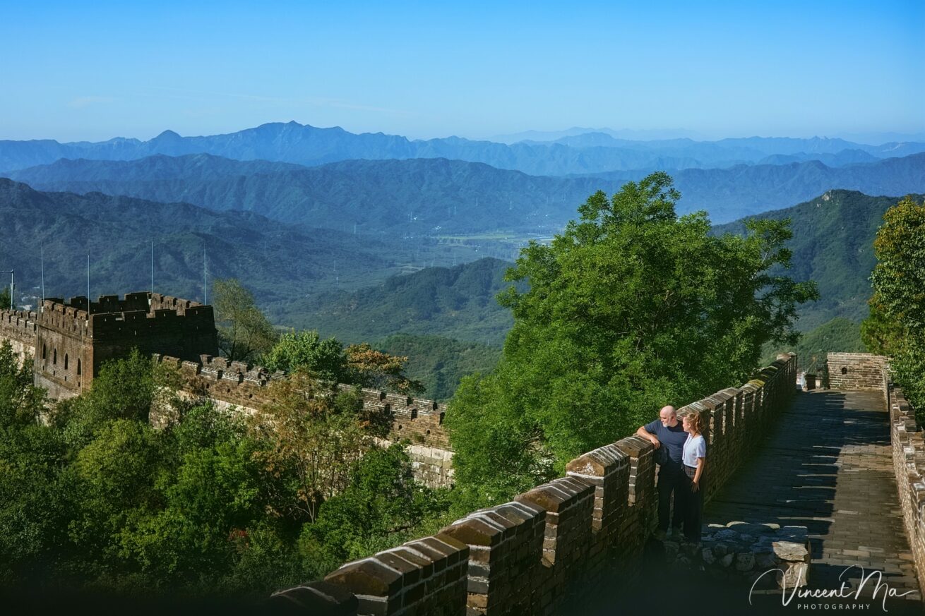 An American couple posing for romantic pictures against the backdrop of Mutianyu Great Wall in Beijing, China. The Great Wall winds through the mountains, and the couple shows their love in the photos
