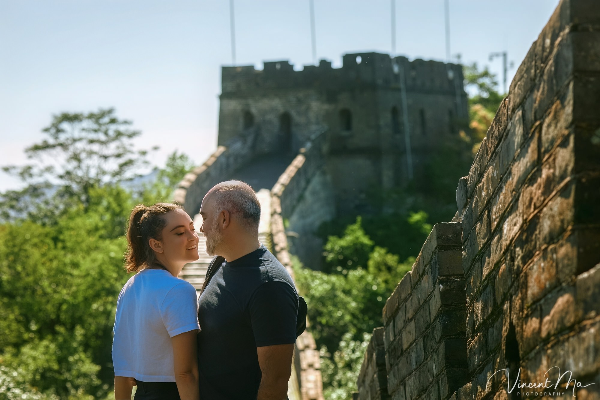 An American couple posing for romantic pictures against the backdrop of Mutianyu Great Wall in Beijing, China. The Great Wall winds through the mountains, and the couple shows their love in the photos
