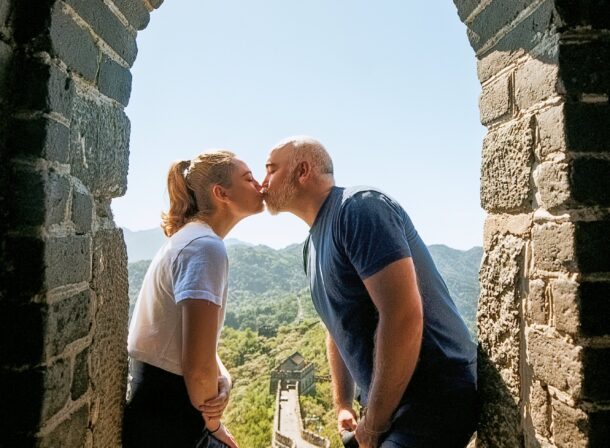 An American couple posing for romantic pictures against the backdrop of Mutianyu Great Wall in Beijing, China. The Great Wall winds through the mountains, and the couple shows their love in the photos