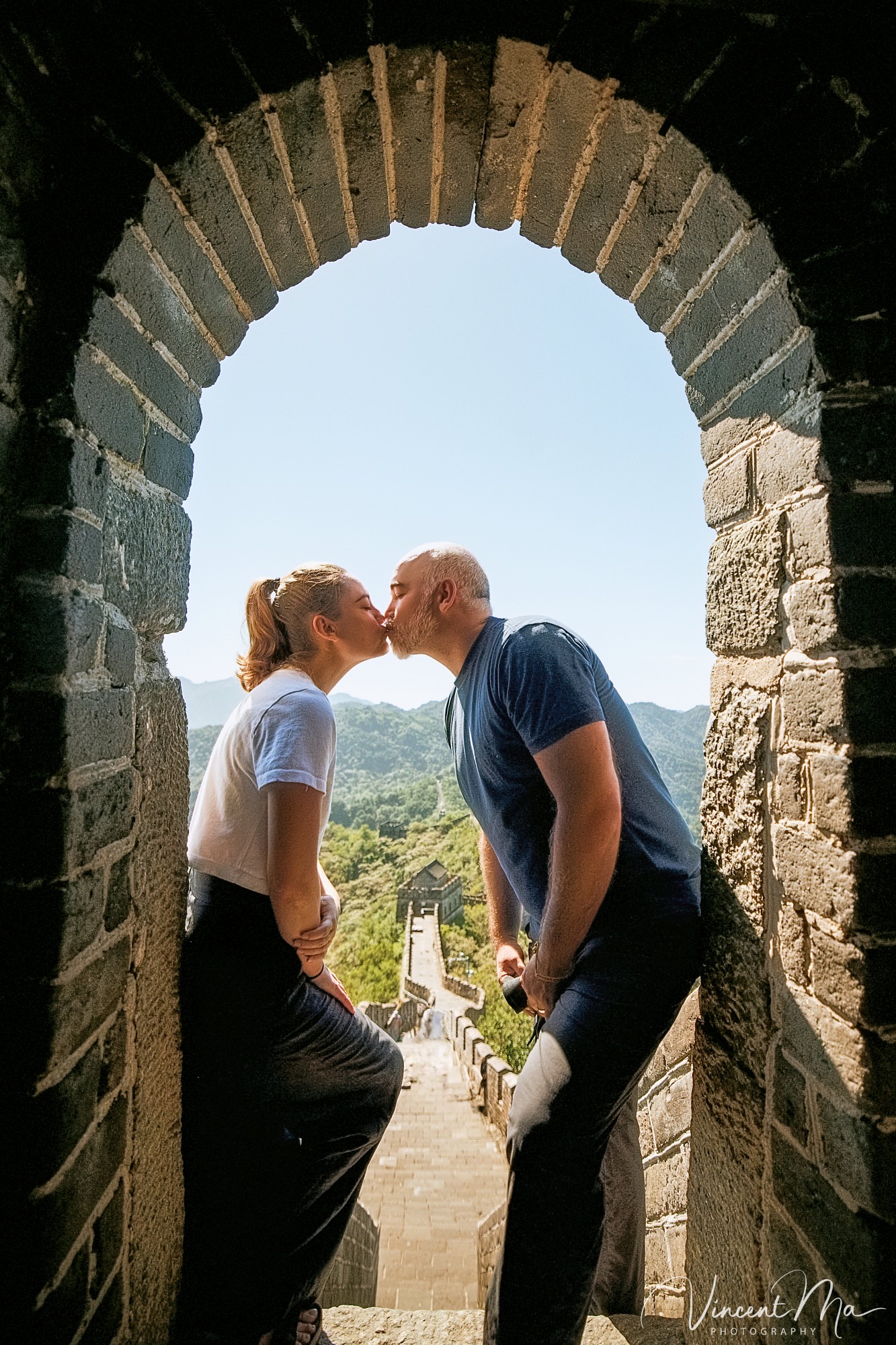 An American couple posing for romantic pictures against the backdrop of Mutianyu Great Wall in Beijing, China. The Great Wall winds through the mountains, and the couple shows their love in the photos