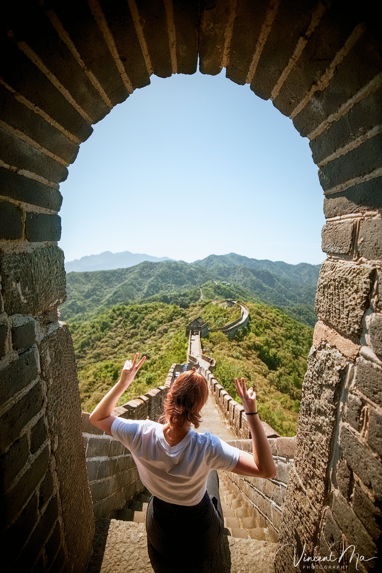 An American couple posing for romantic pictures against the backdrop of Mutianyu Great Wall in Beijing, China. The Great Wall winds through the mountains, and the couple shows their love in the photos