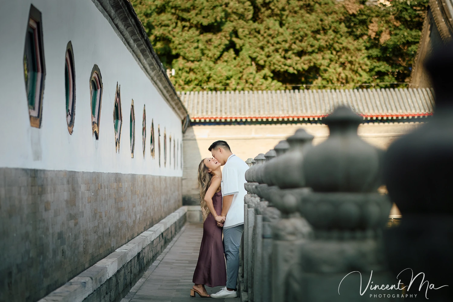 Couple enjoying a romantic moment at The Long Corridor in Beijing's Summer Palace, surrounded by traditional Chinese garden scenery with lakes and pavilions. Engagement shooting in summer palace. 