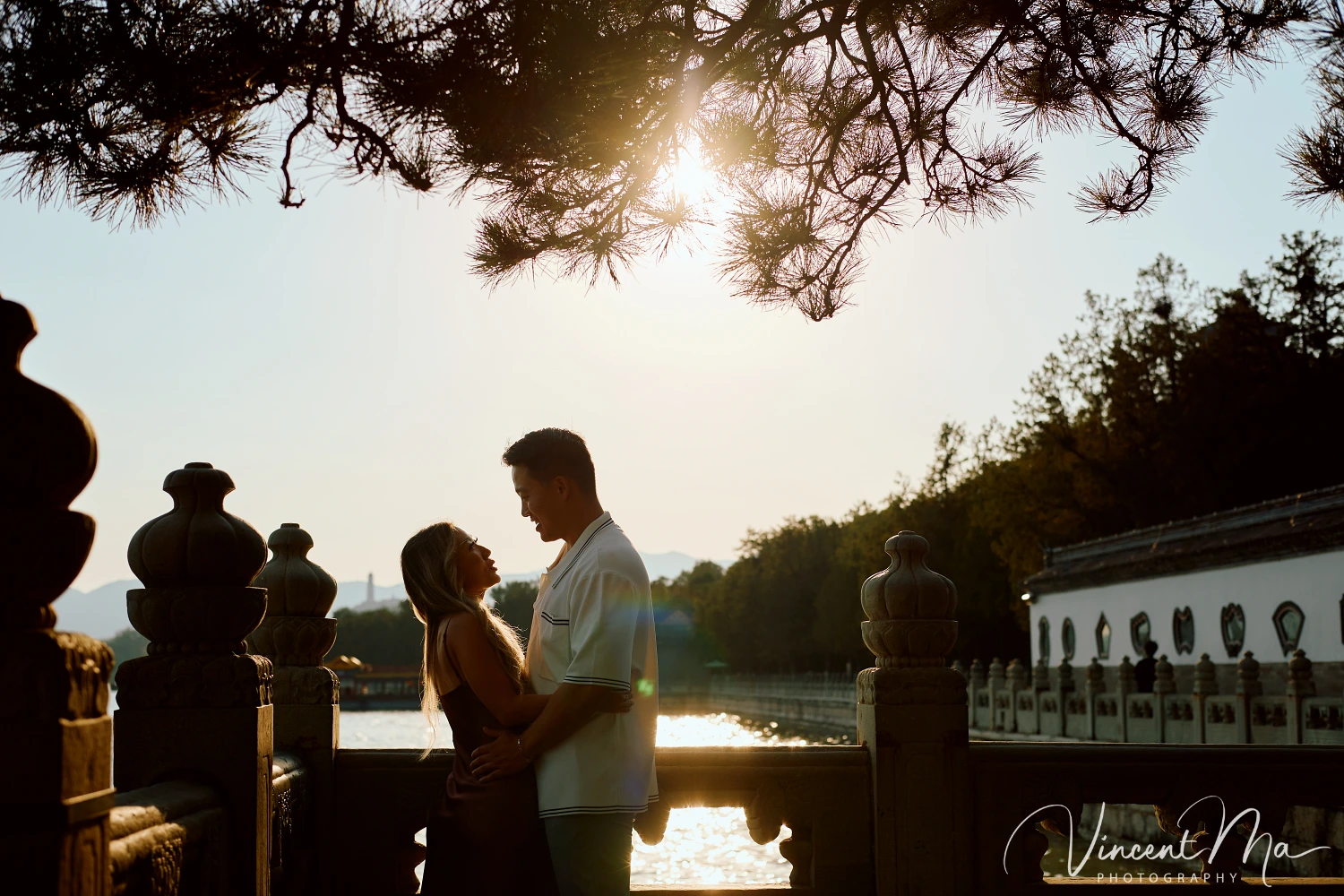 Couple enjoying a romantic moment at The Long Corridor in Beijing's Summer Palace, surrounded by traditional Chinese garden scenery with lakes and pavilions. Engagement shooting in summer palace. 