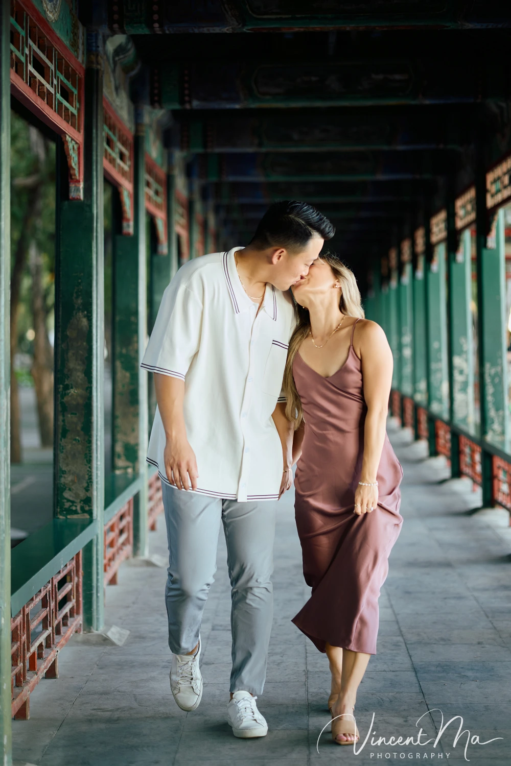 Couple enjoying a romantic moment at The Long Corridor in Beijing's Summer Palace, surrounded by traditional Chinese garden scenery with lakes and pavilions. Engagement shooting in summer palace. 