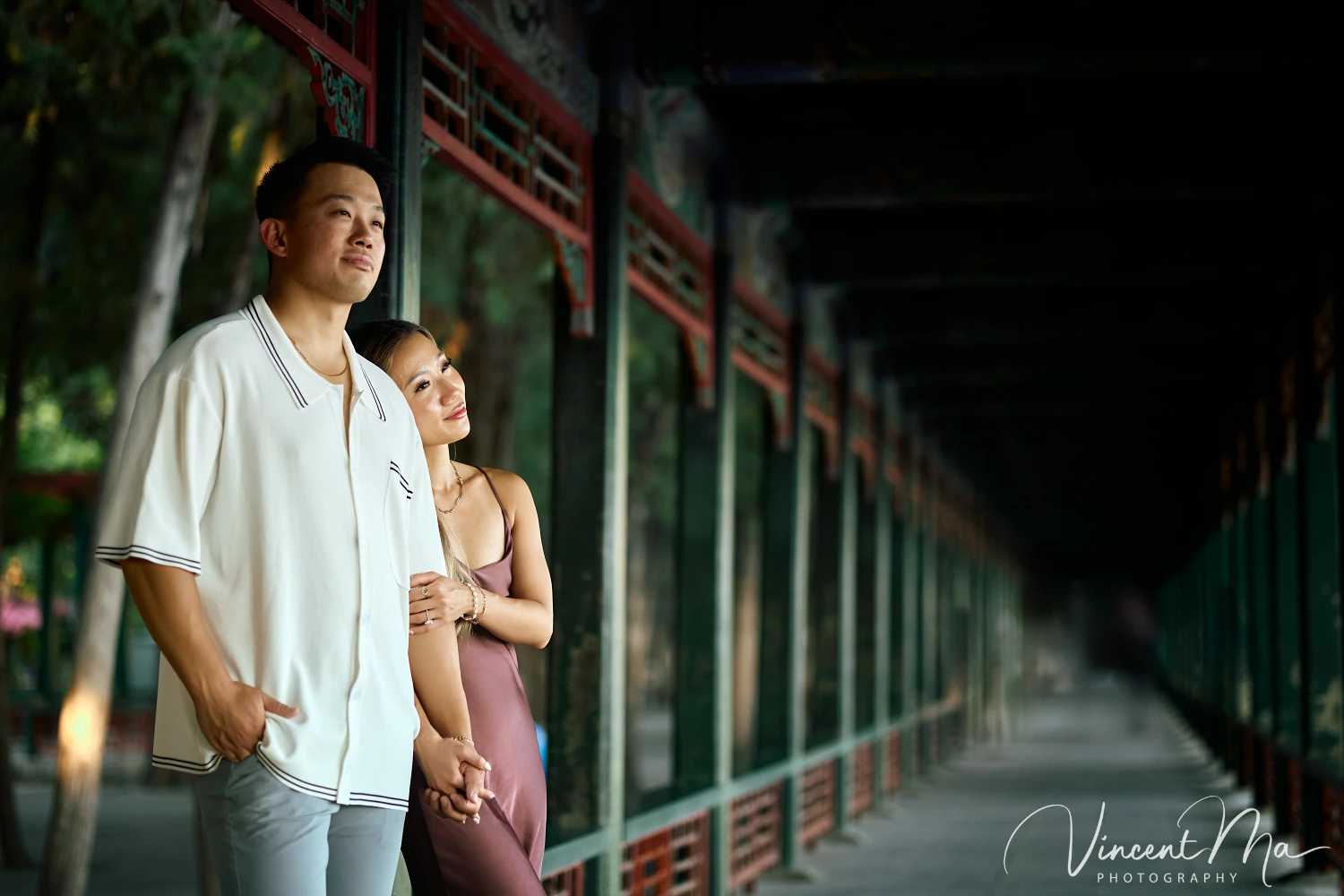 Couple enjoying a romantic moment at The Long Corridor in Beijing's Summer Palace, surrounded by traditional Chinese garden scenery with lakes and pavilions. 