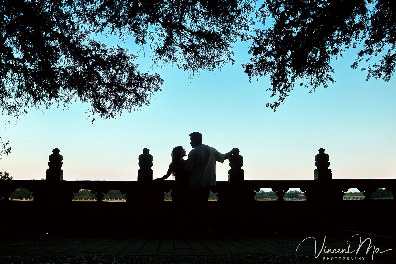 A couple shares an intimate moment with the magnificent architecture of the Summer Palace in sunset in the background.