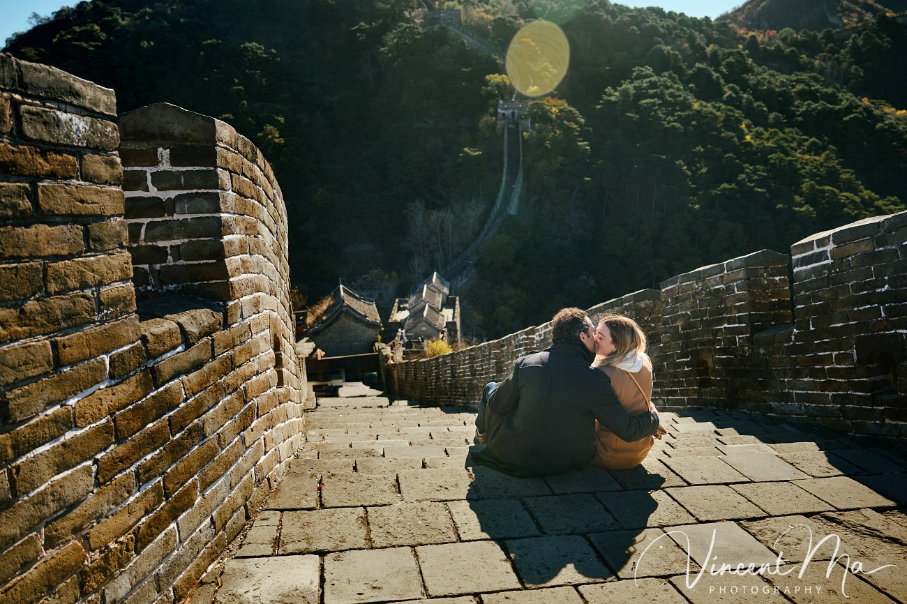 Man proposing to woman on Mutianyu Great Wall during autumn with mountains in background