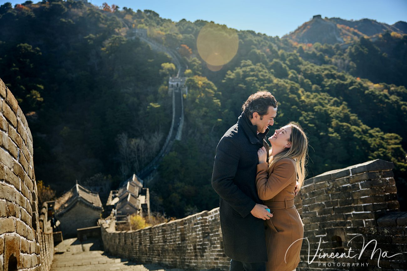 Man proposing to woman on Mutianyu Great Wall during autumn with mountains in background