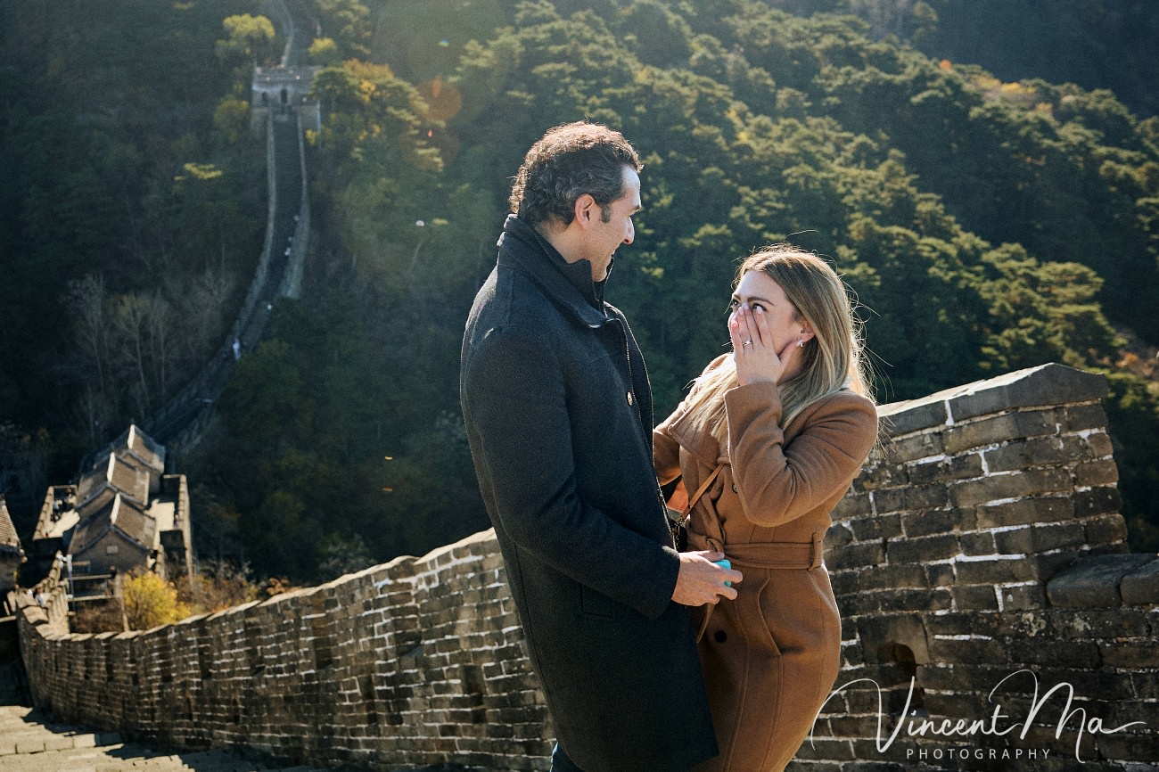 Man proposing to woman on Mutianyu Great Wall during autumn with mountains in background