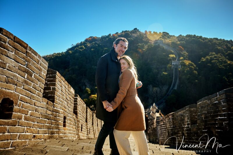 Man proposing to woman on Mutianyu Great Wall during autumn with mountains in background