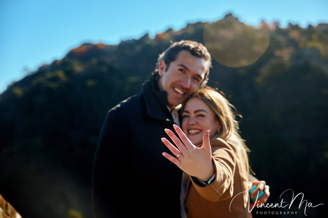 Man proposing to woman on Mutianyu Great Wall during autumn with mountains in background