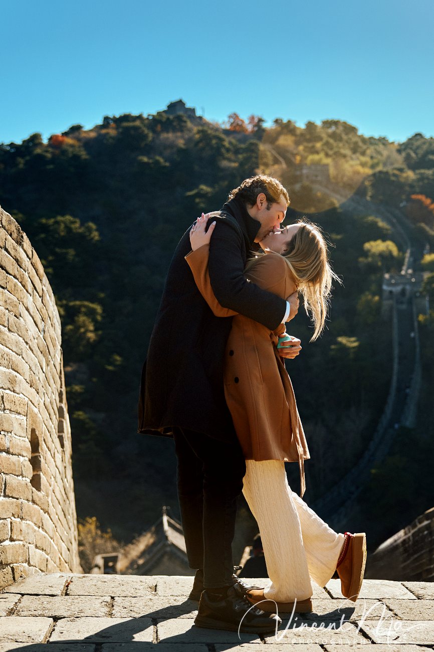 Man proposing to woman on Mutianyu Great Wall during autumn with mountains in background