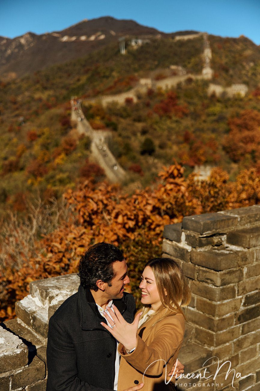 Surprise marriage proposal engagement shooting on Mutianyu Great Wall with ancient bricks and autumn leaves in background