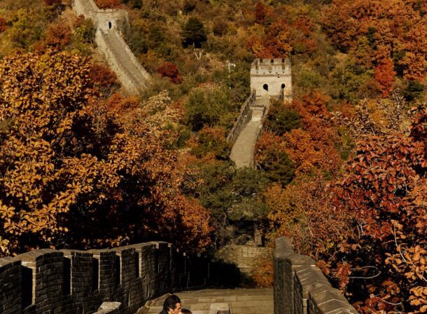Surprise marriage proposal engagement shooting on Mutianyu Great Wall with ancient bricks and autumn leaves in background