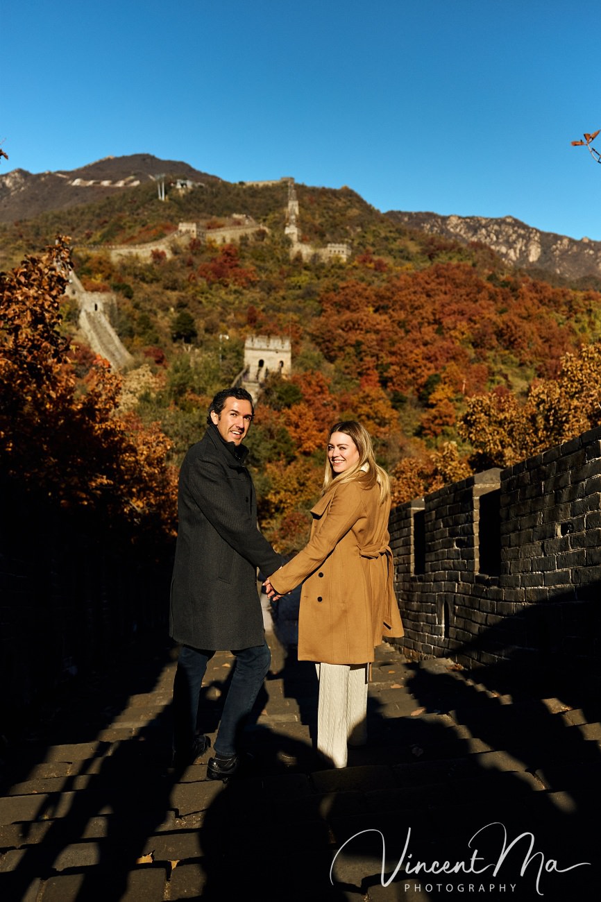 Surprise marriage proposal engagement shooting on Mutianyu Great Wall with ancient bricks and autumn leaves in background