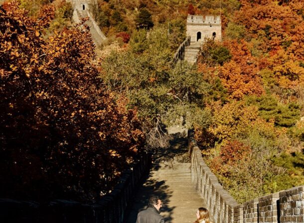 Surprise marriage proposal engagement shooting on Mutianyu Great Wall with ancient bricks and autumn leaves in background