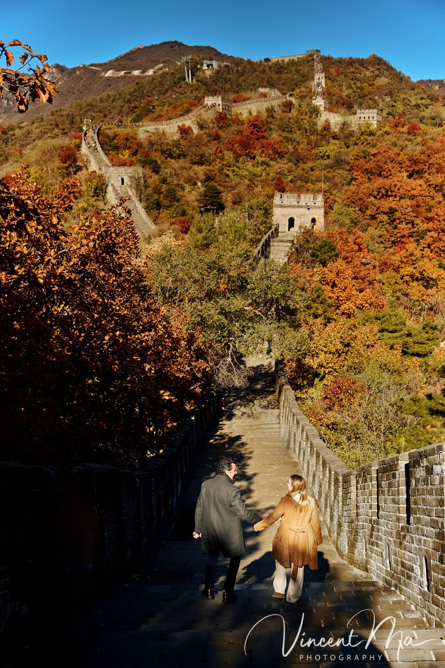 Surprise marriage proposal engagement shooting on Mutianyu Great Wall with ancient bricks and autumn leaves in background