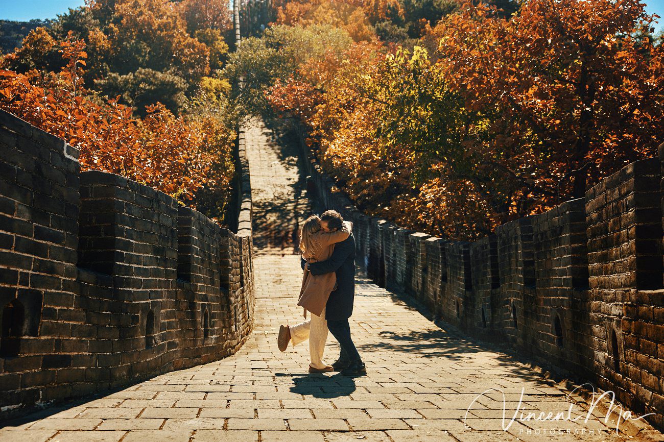 Surprise marriage proposal engagement shooting on Mutianyu Great Wall with ancient bricks and autumn leaves in background