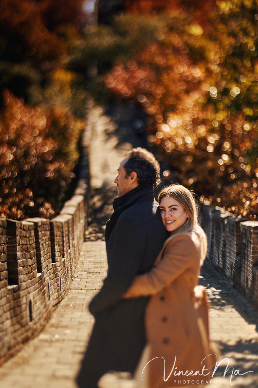Surprise marriage proposal engagement shooting on Mutianyu Great Wall with ancient bricks and autumn leaves in background