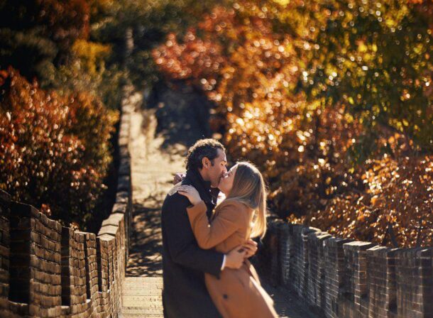 Surprise marriage proposal engagement shooting on Mutianyu Great Wall with ancient bricks and autumn leaves in background