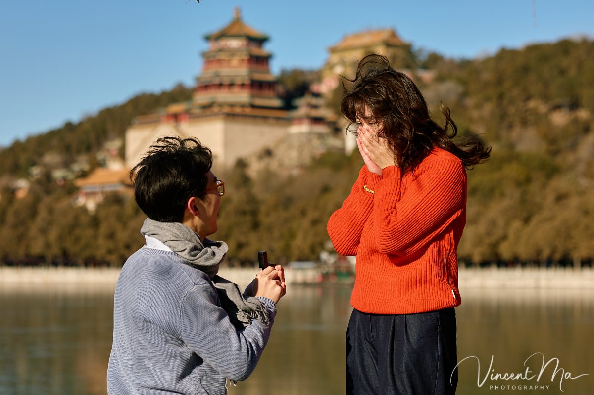 Beijing proposal.Couple sharing a romantic kiss with the Tower of Buddhist Incense in the background at the Summer Palace, Beijing. Winter engagement photography with clear blue sky