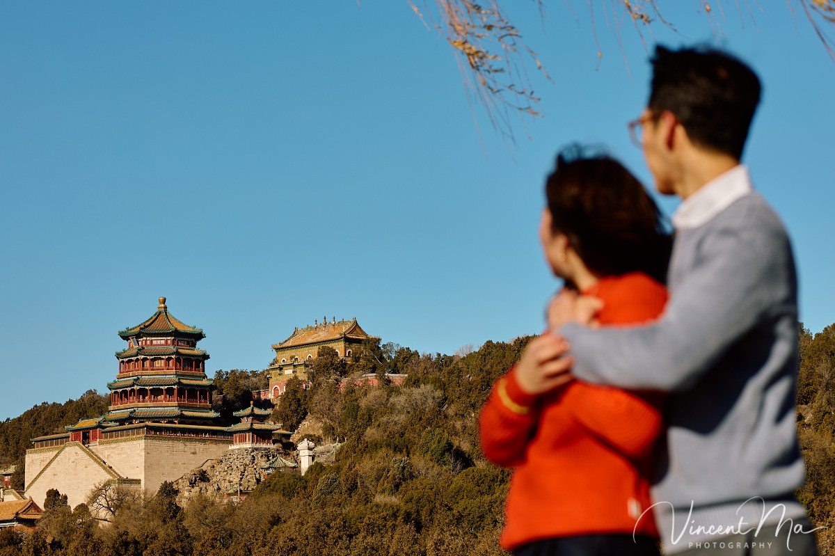 Beijing proposal.Couple sharing a romantic kiss with the Tower of Buddhist Incense in the background at the Summer Palace, Beijing. Winter engagement photography with clear blue sky
