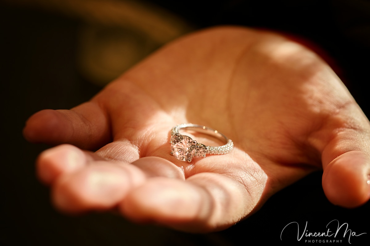 Beijing proposal.Close-up macro shot of a diamond engagement ring resting in the palm of a hand, illuminated by warm sunlight. Highlighting the sparkle and detail of the ring.